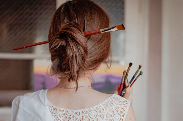 Young woman holding paint brushes
