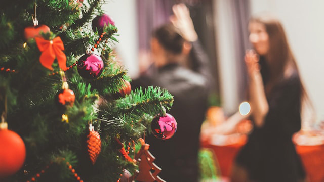 A Christmas tree with people socialising in the background
