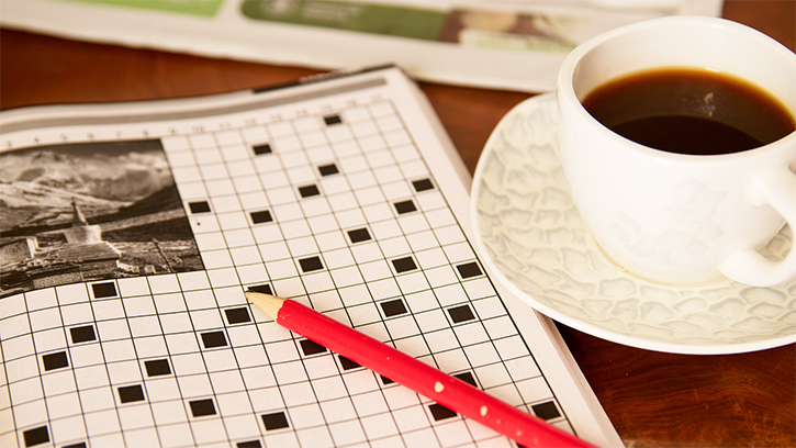 A wordsearch puzzle with a red pencil and accompanying cup of coffee