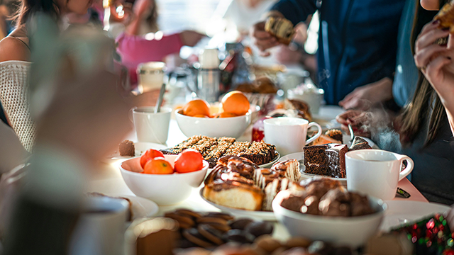 Breakfast Social - Brunch and Banter. A breakfast buffet, with fruit, coffee and pastries, layed out along a table disappearing out of focus.