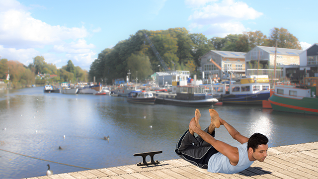 Pilates – River Flow. Man on dock pulls pilates pose, overlooking Swan island and the river