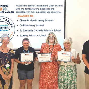 YCiS - Excellence Award 2026 banner. Image shows RCC and school staff holding certificates. The 5 staff members are standing in front of a projector screen displaying details of the award.